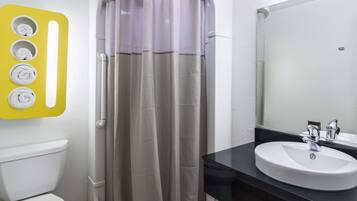 A bathroom with a shower curtain, a toilet, a sink, and a mirror.