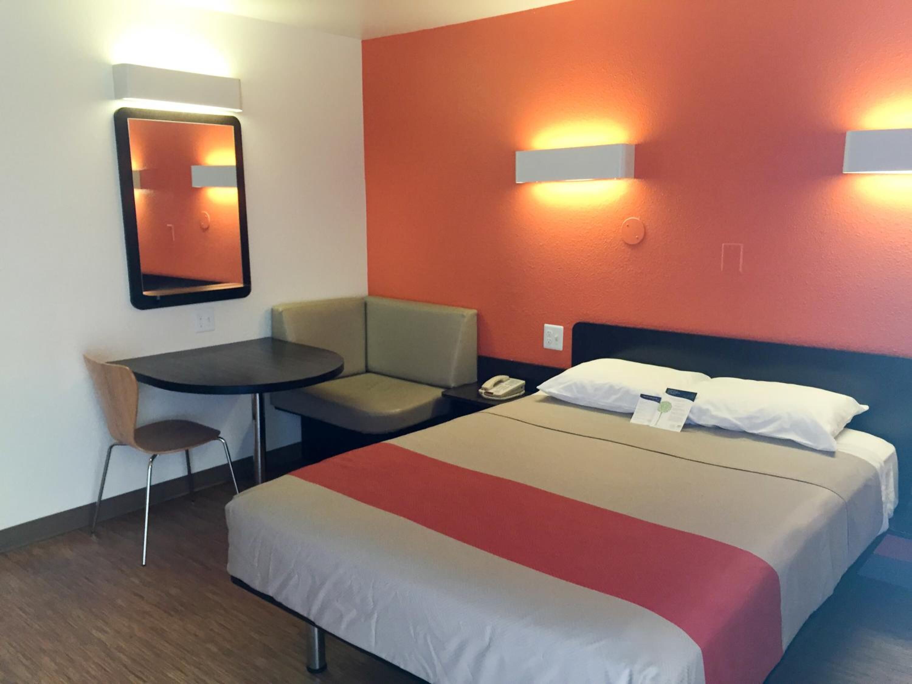 Una habitación de hotel con cama, escritorio, silla y espejo.