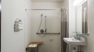 Un baño pequeño y limpio con ducha, lavamanos, espejo y toallero.