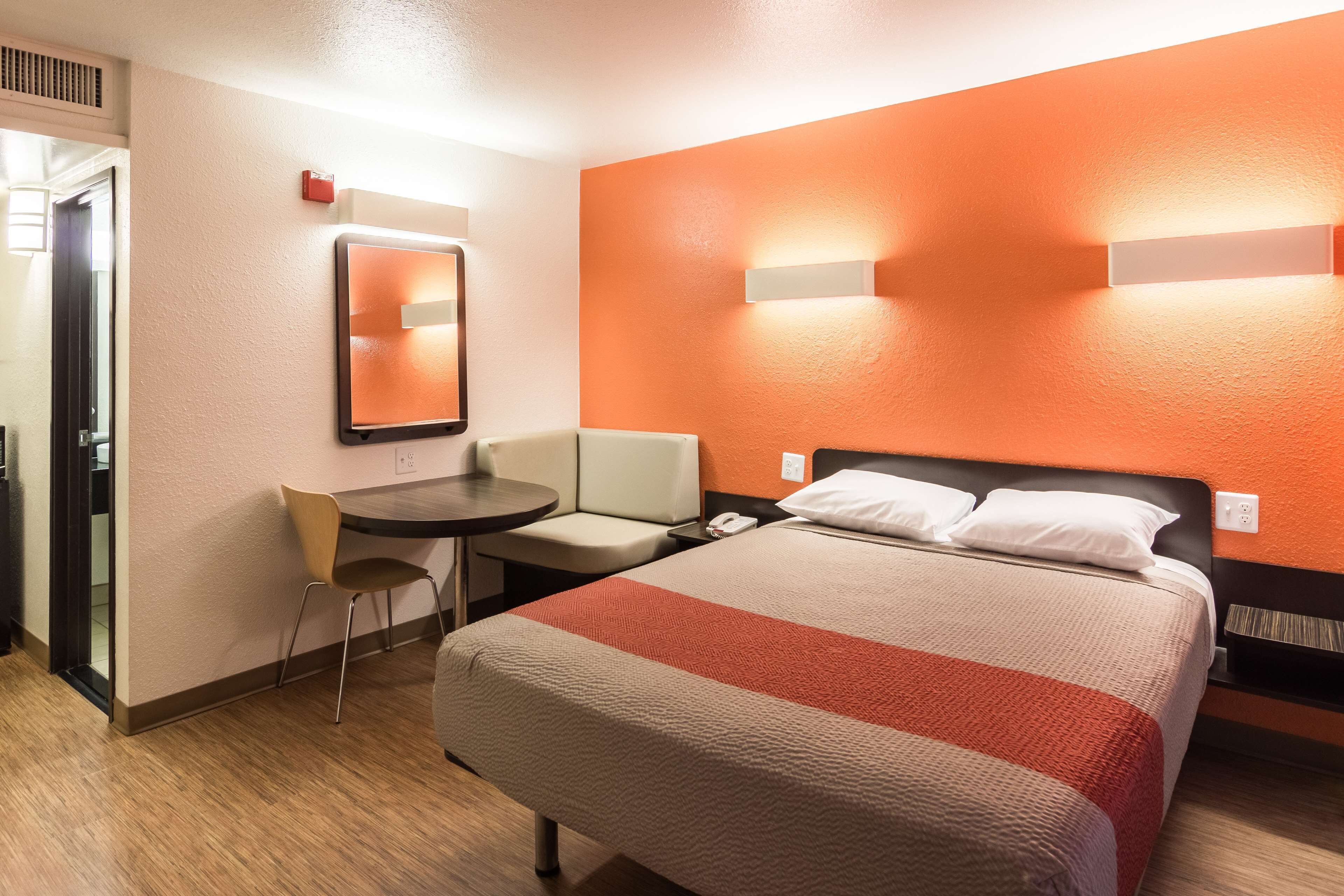 Ein Hotelzimmer mit Bett, Schreibtisch, Stuhl und Spiegel.