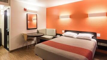 Ein Hotelzimmer mit Bett, Schreibtisch, Stuhl und Spiegel.