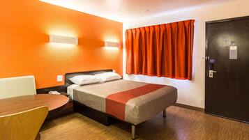 A hotel room with a bed, a desk, and a chair.