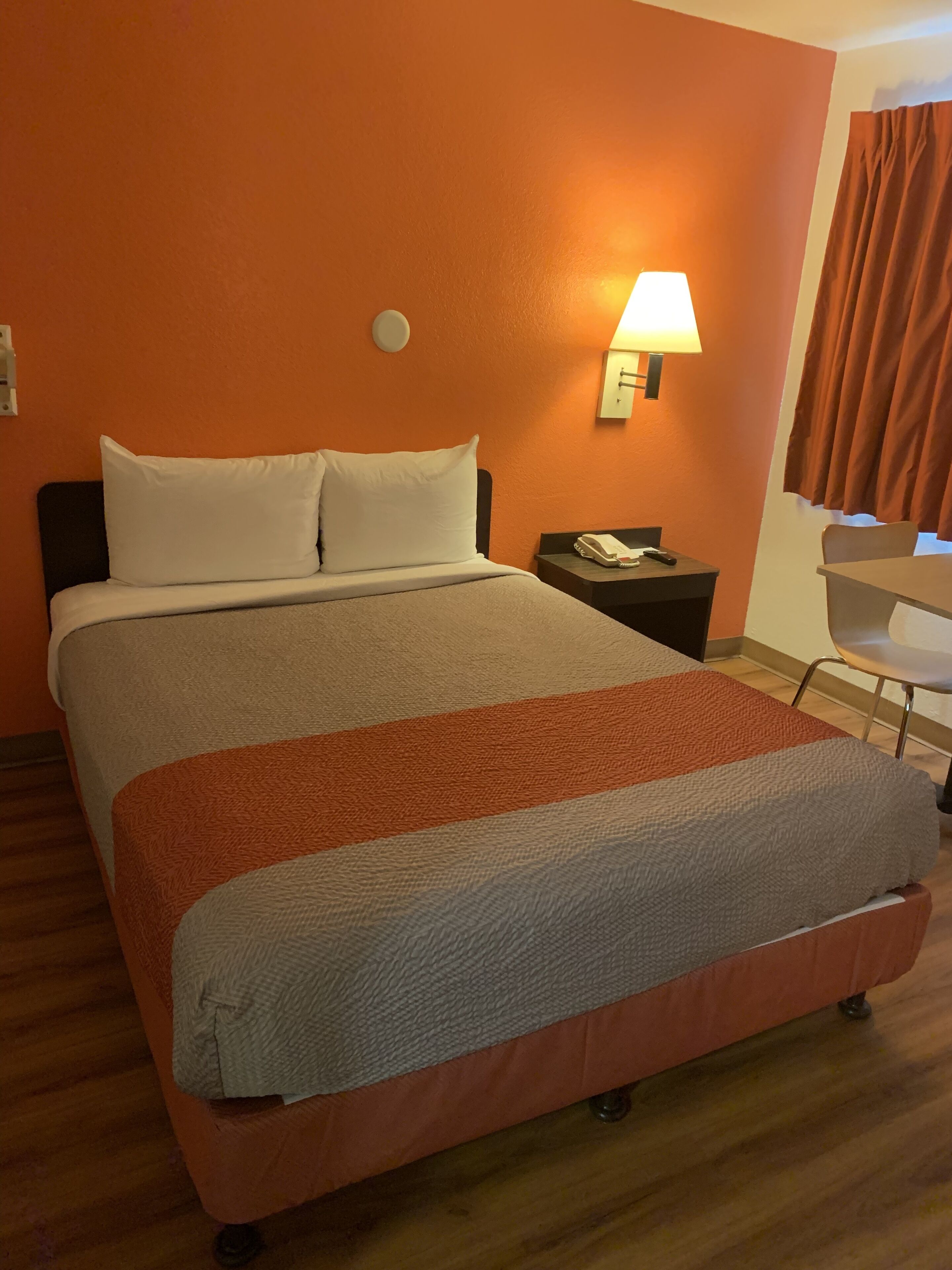 Une chambre d’hôtel avec un grand lit, une table de chevet avec une lampe et une chaise.