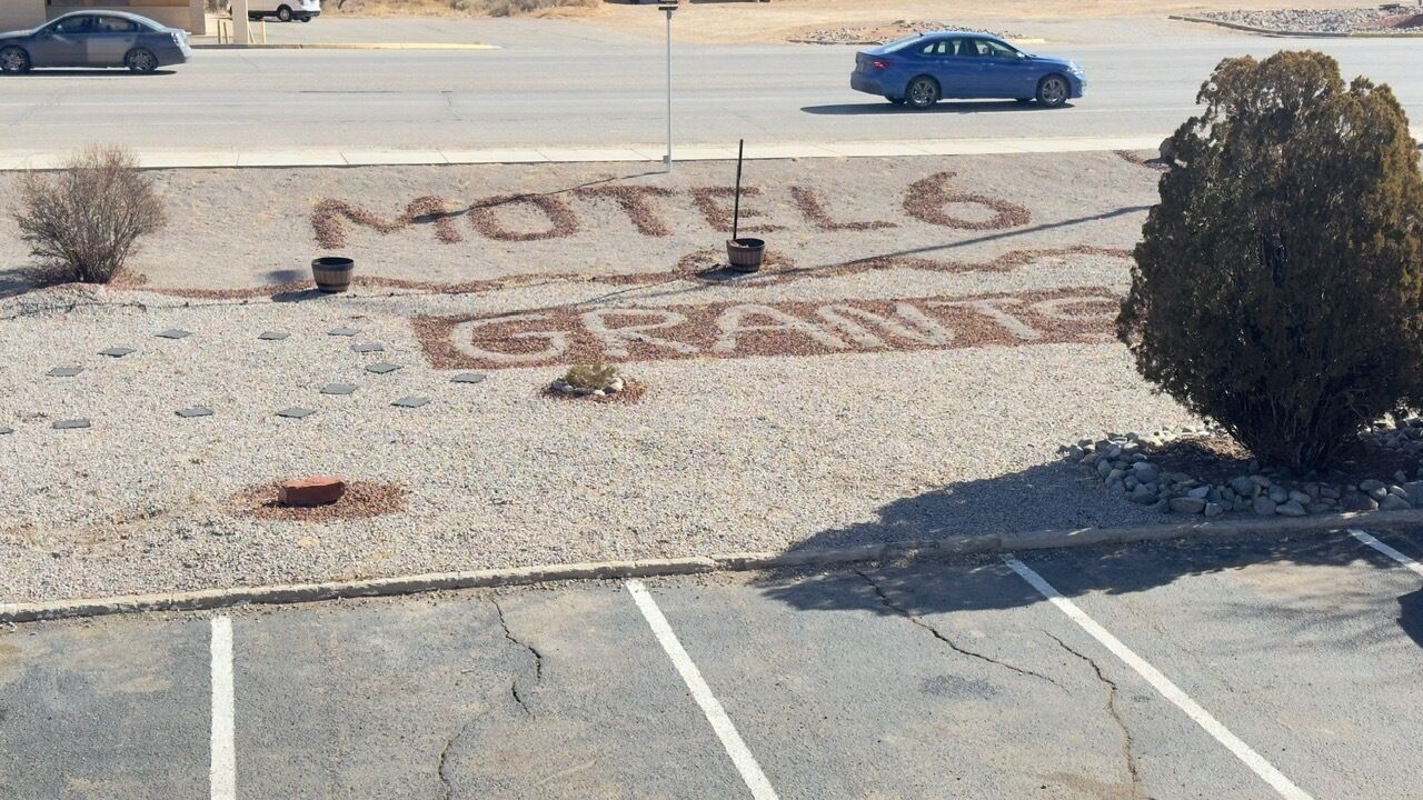 Um estacionamento com uma placa pintada que diz 'Motel 6 Grapes'.