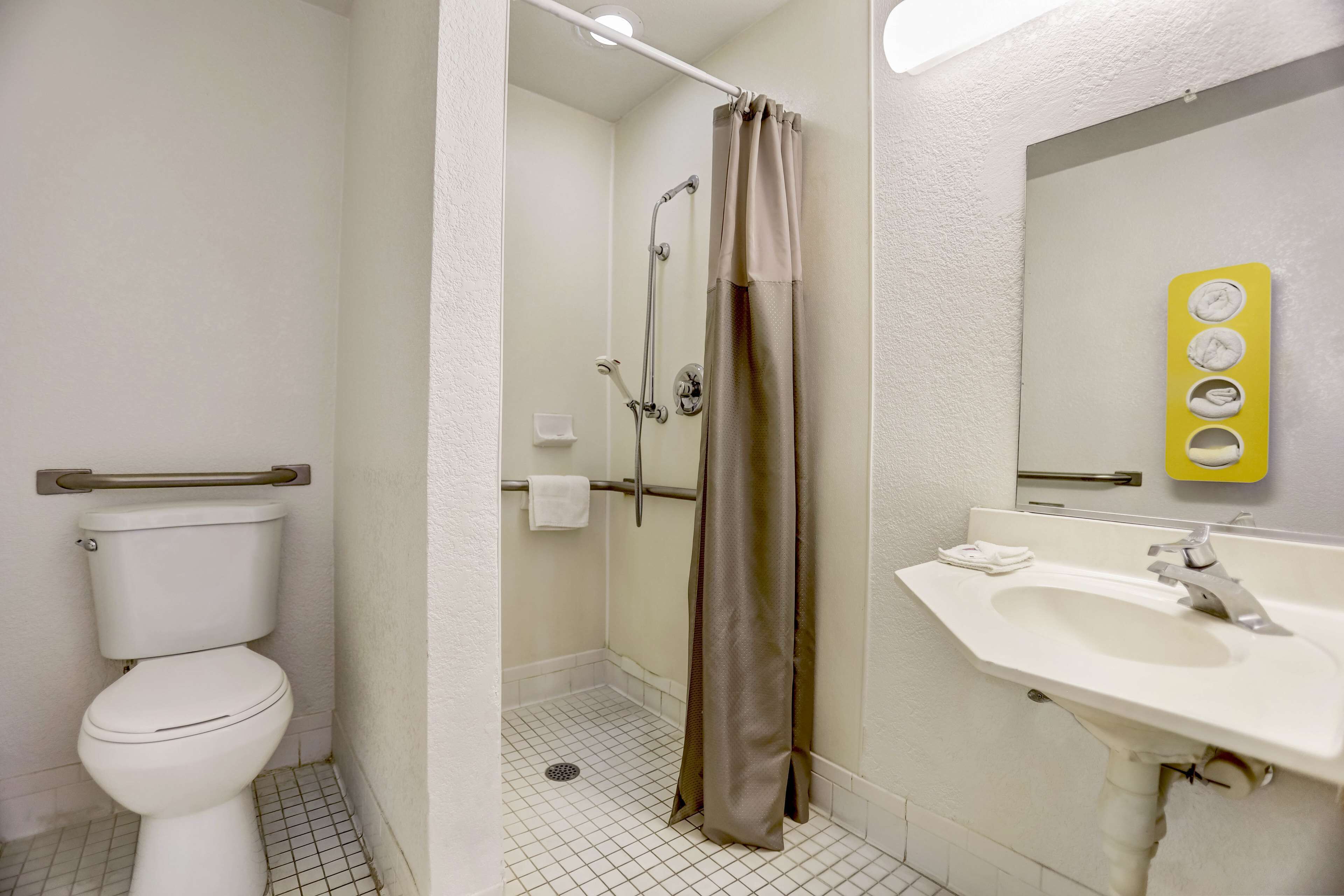 Et badeværelse med toilet, bruser og håndvask.