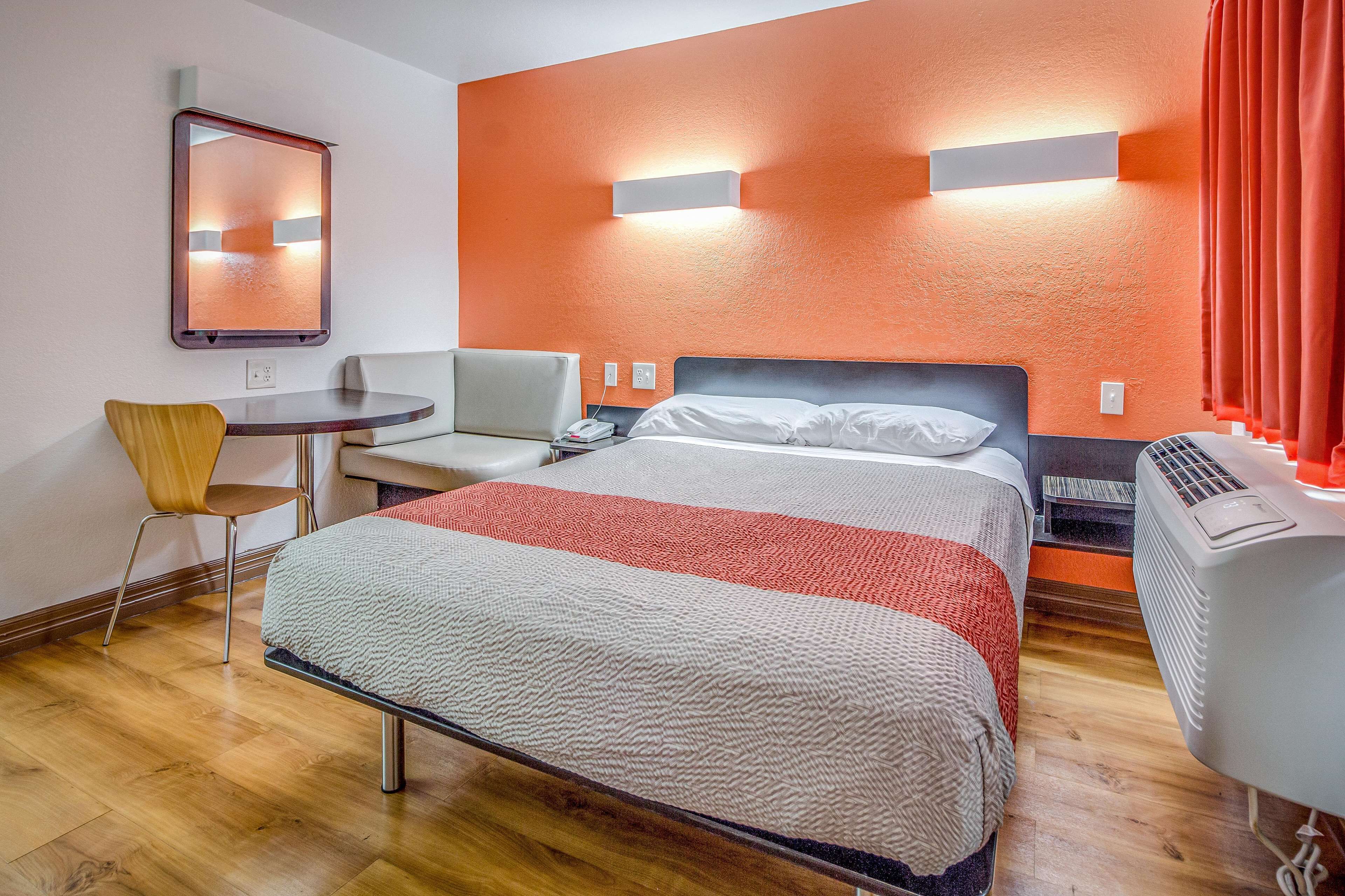 Een hotelkamer met een bed, een bureau, een stoel en een verwarming.