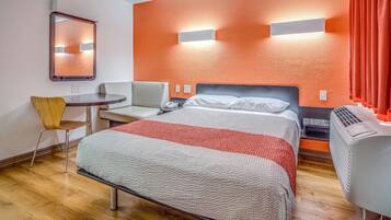 Een hotelkamer met een bed, een bureau, een stoel en een verwarming.