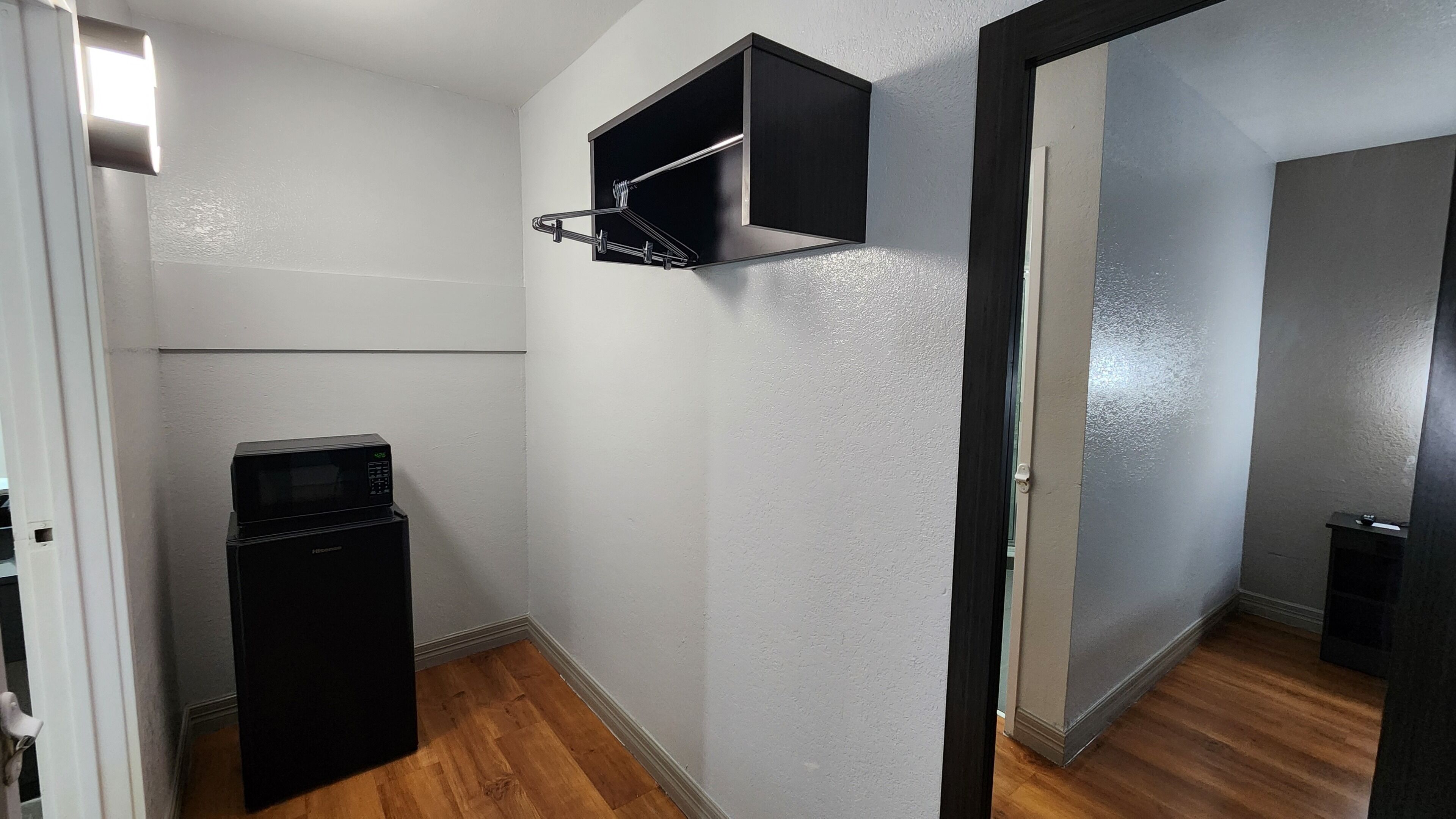 Ein kleines Zimmer mit einer Mikrowelle, einer kleinen Schrank und einer Tür zu einem weiteren Bereich.