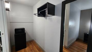 Ein kleines Zimmer mit einer Mikrowelle, einer kleinen Schrank und einer Tür zu einem weiteren Bereich.