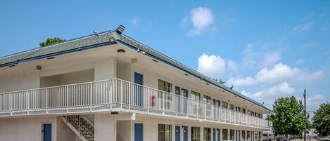 A motel with a two-story structure, a covered walkway, and a parking lot.
