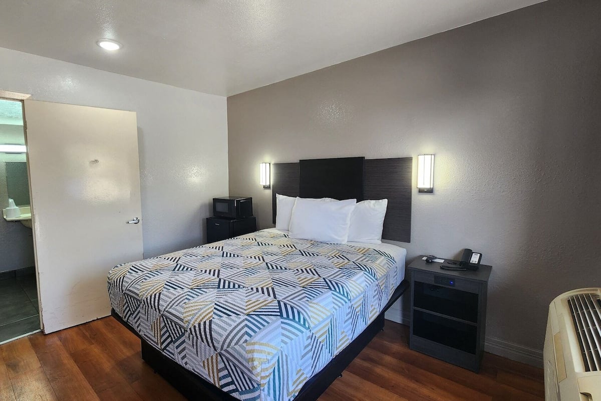 A hotel room with a bed, bedside tables, a TV, and a mirror.