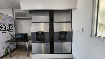 Una kitchenette con microondas, dos dispensadores de agua y aire acondicionado de pared.