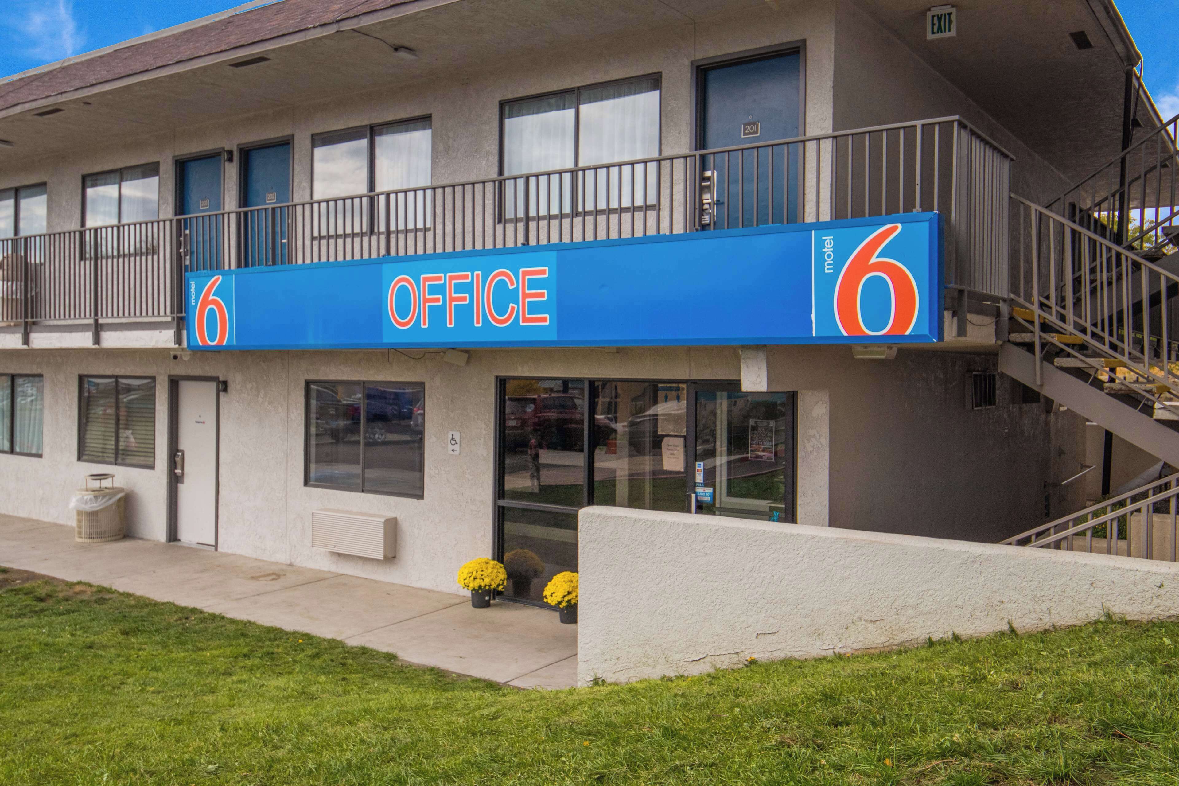 A motel with a prominent '6 OFFICE' sign, a balcony, and a staircase leading to an upper level.