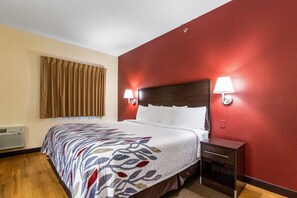 A hotel room with a bed, two bedside lamps, a nightstand, and a window with curtains. - Red Roof Inn Georgetown, IN - Louisville West (Georgetown)