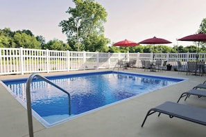 A rectangular swimming pool with a metal ladder, surrounded by a white picket fence. - Red Roof Inn Georgetown, IN - Louisville West (Georgetown)