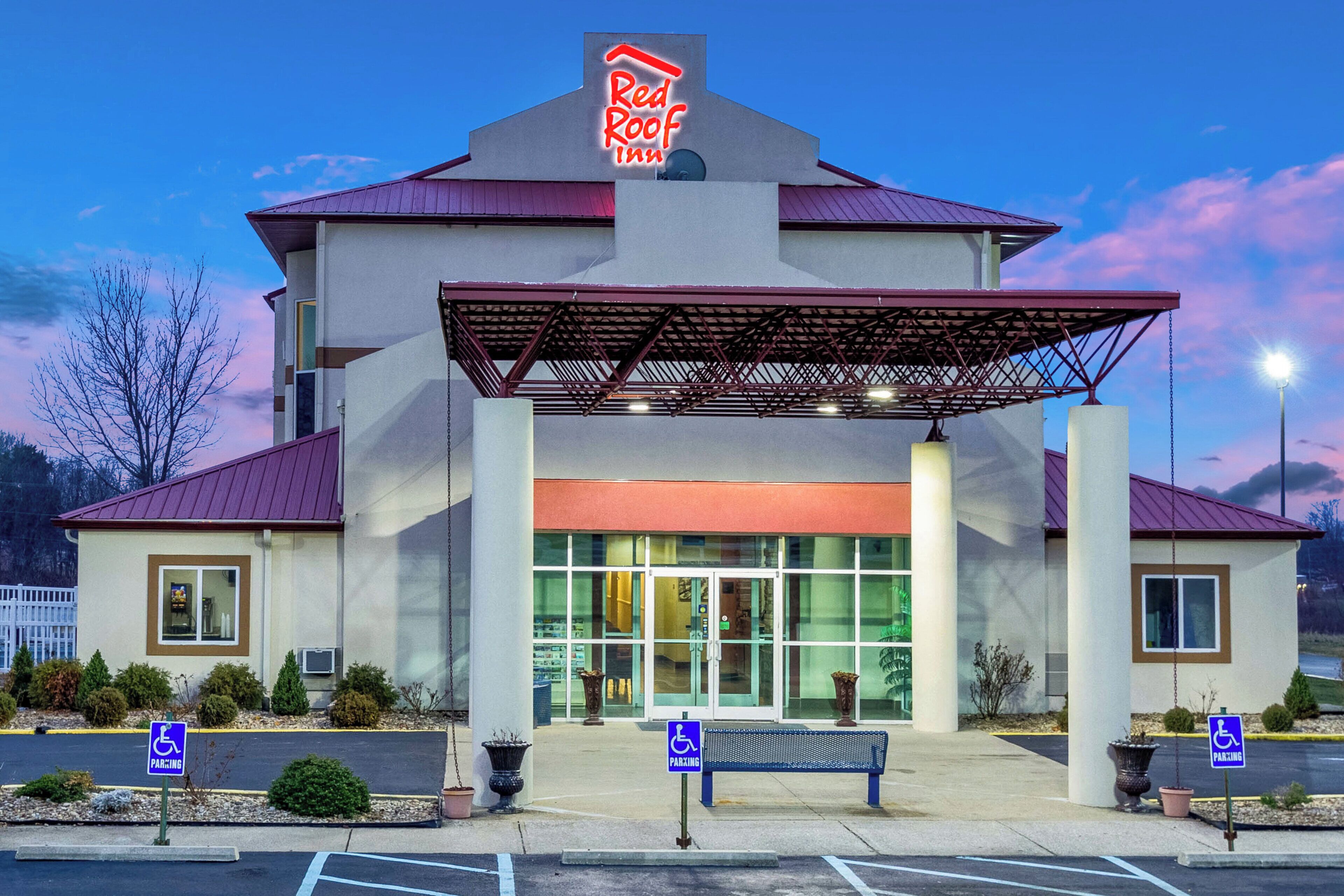 Un hôtel Red Roof Inn doté d’une entrée abritée, de places de stationnement réservées aux personnes handicapées et d’un parking.
