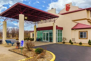 A Red Roof Inn with a covered parking area, a handicap accessible parking sign, and a building entrance with glass doors. - Red Roof Inn Georgetown, IN - Louisville West (Georgetown)