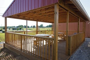 A covered outdoor deck with wooden furniture and a metal railing. - Red Roof Inn Georgetown, IN - Louisville West (Georgetown)