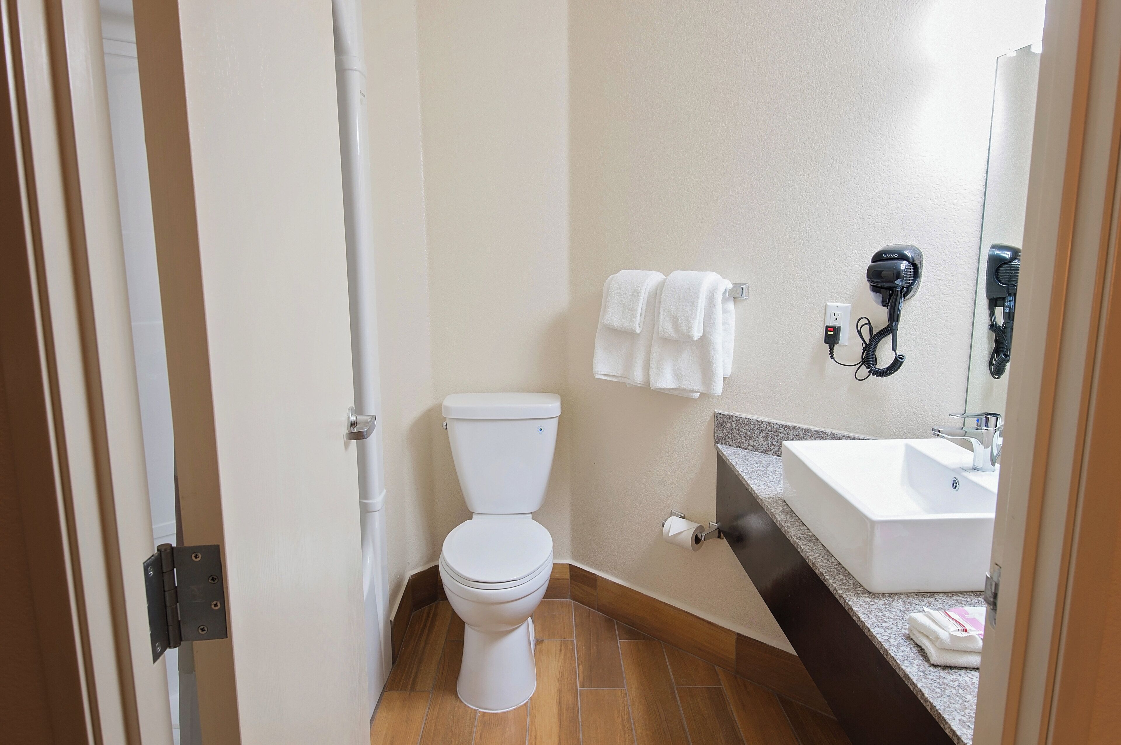 A bathroom with a toilet, a sink, and a hairdryer mounted on the wall.