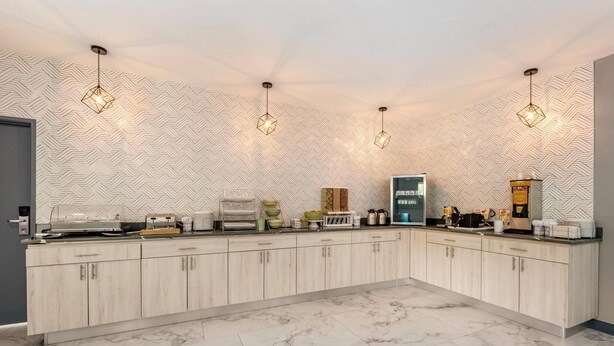 A modern kitchen with a herringbone-patterned backsplash, marble flooring, and pendant lighting. - Quality Inn Ruidoso (Ruidoso)