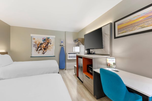 Een hotelkamer met twee bedden, een bureau met stoel, een televisie en kunstwerken aan de muur.