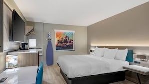 A modern hotel room with a bed, bedside table, desk, chair, TV, and a painting on the wall. - Quality Inn Ruidoso (Ruidoso)