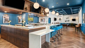 Una cocina moderna con una isla central, taburetes de bar y una mesa de billar.