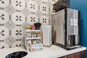 A kitchenette with a coffee machine, a trash bin, and a shelf with packaged goods. - The Ellsworth Hotel, an Ascend Collection Hotel (Williams)