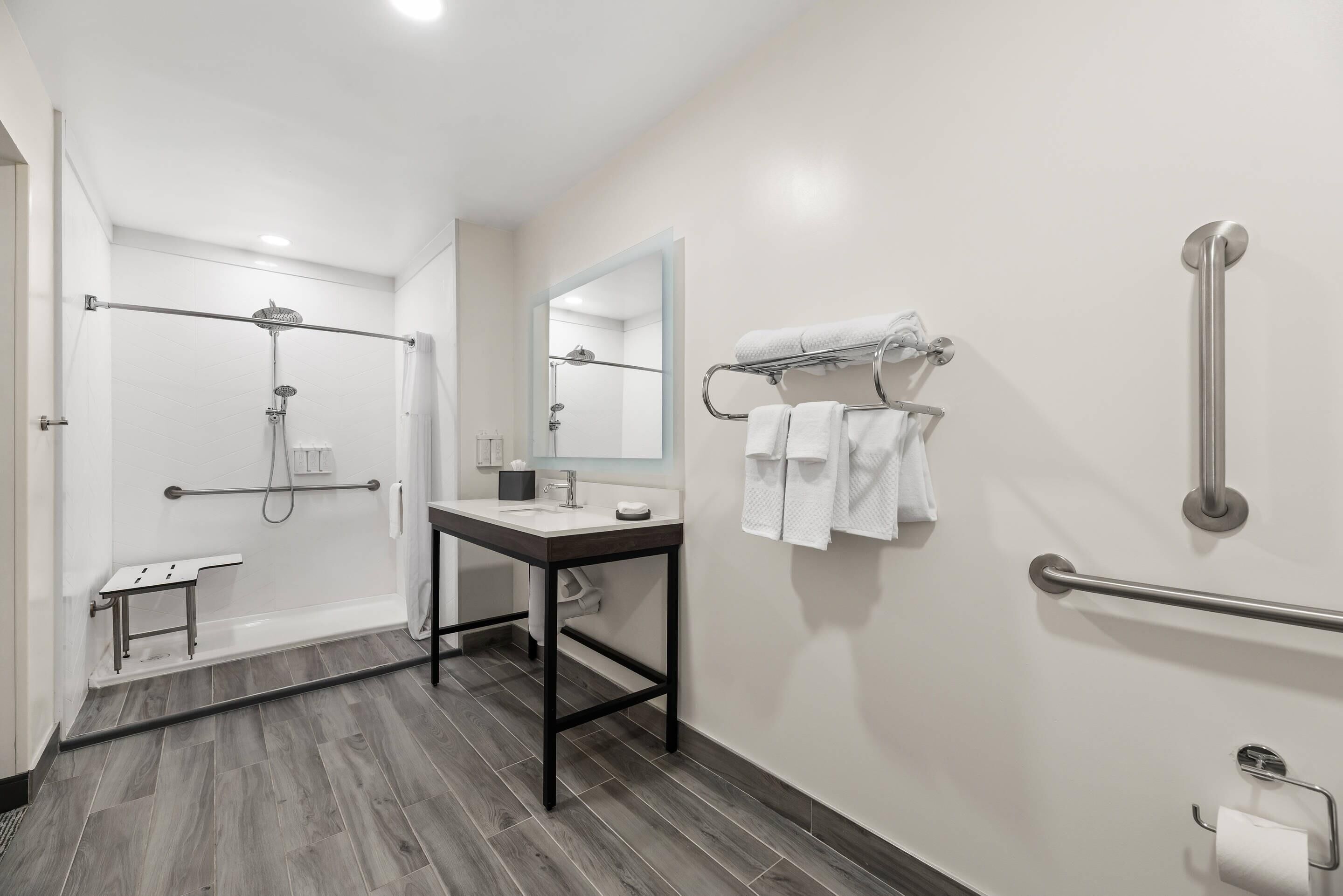 Un baño moderno con ducha, lavabo, espejo y perchero.