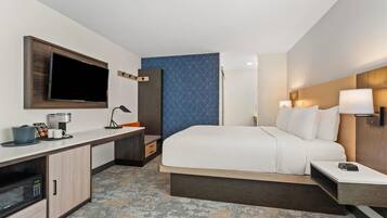 Habitación de hotel con cama, escritorio, televisor de pantalla plana, cafetera y microondas.
