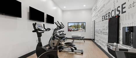 A modern gym with stationary bikes, a treadmill, and a rowing machine.