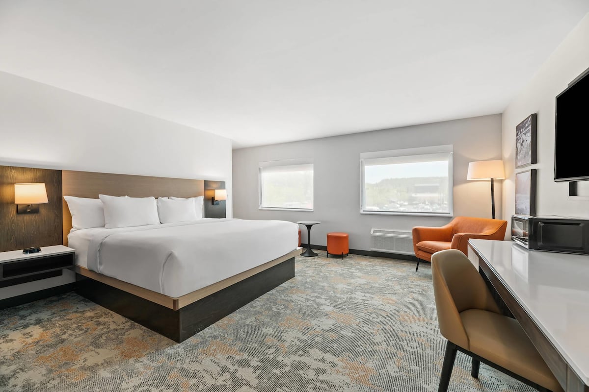 Ein Hotelzimmer mit einem Bett, einem Schreibtisch, einem Stuhl, einem Fernseher und einem Fenster.