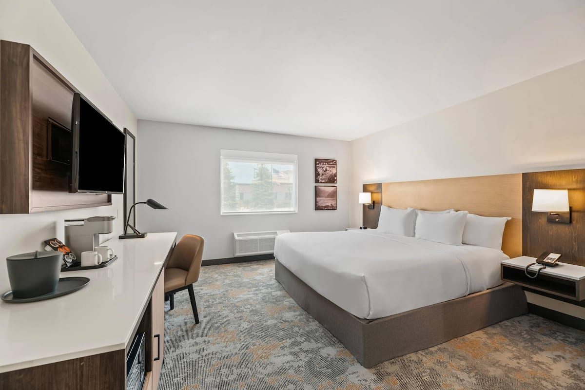 Ein Hotelzimmer mit Bett, Schreibtisch, Stuhl und Fernseher.