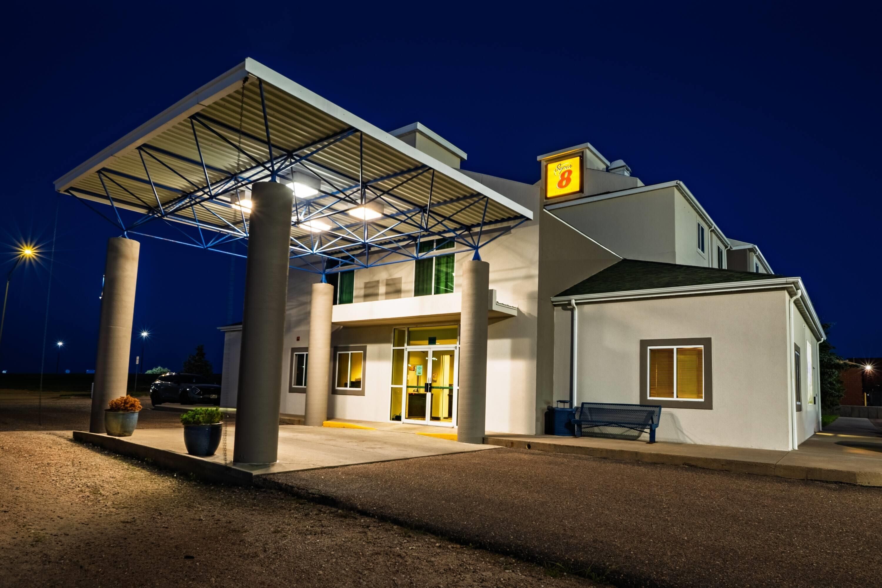 A building with a covered entrance, large pillars, and a sign indicating a location.