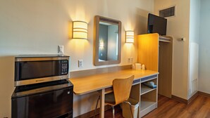 A compact kitchenette with a microwave, a small refrigerator, a wooden desk, a chair, and a mirror. - Super 8 by Wyndham Sidney NE I-80 (Sidney)