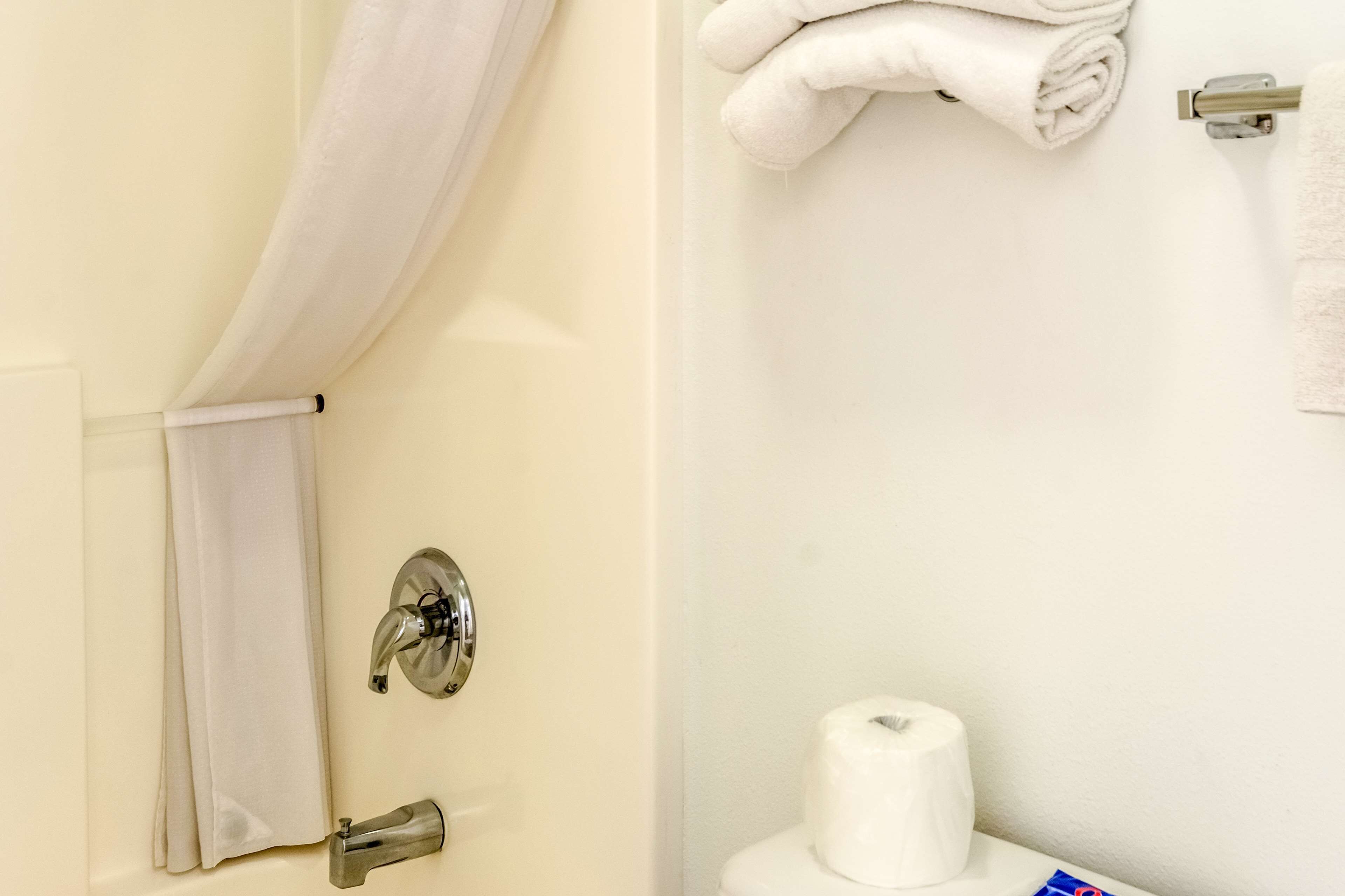 A bathroom with a toilet, a towel rack, and a shower curtain.