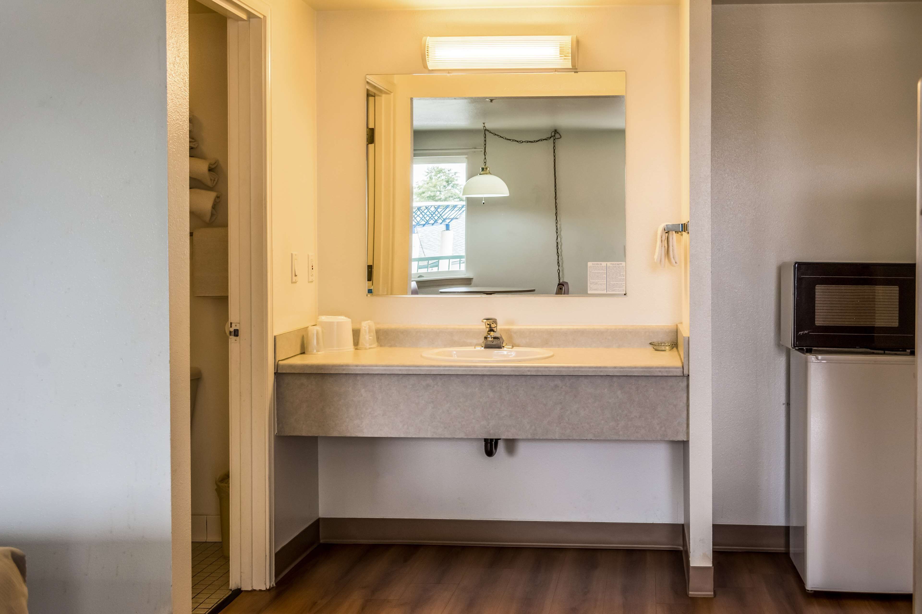 Un baño con lavamanos, espejo y refrigerador.