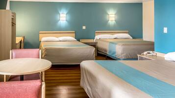 A hotel room with two beds, a small table, and a chair.