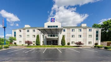 A modern hotel with a covered entrance, multiple floors, and a parking lot.