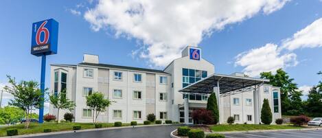 A modern motel with a large sign reading "6 Welcome" and a covered parking area.