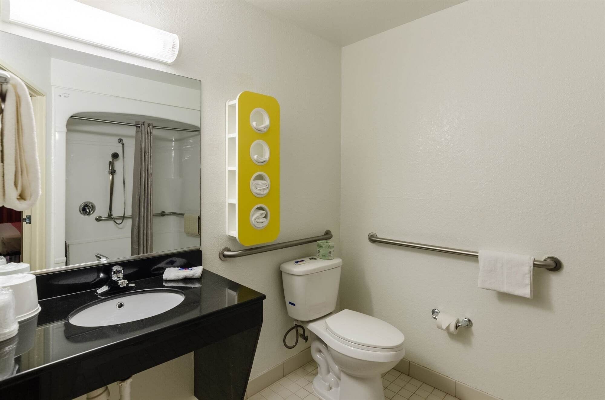A bathroom with a black sink, a toilet, a shower, and a towel rack.