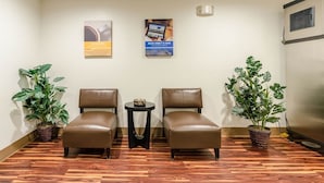 A room with two brown leather chairs, a small table, and two potted plants. - Motel 6 Bristol, VA (Bristol)