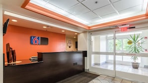 A reception area with a dark reception desk, a number 6 sign, and a glass door leading outside. - Motel 6 Bristol, VA (Bristol)