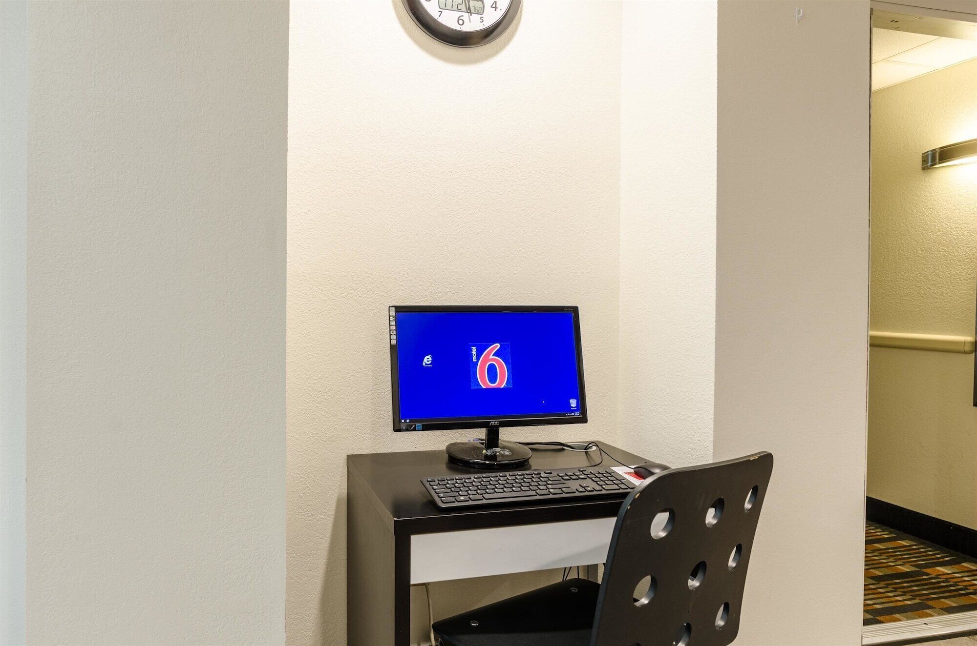 A hotel room with a desk, a computer, and a chair.