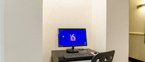 A hotel room with a desk, a computer, and a chair.