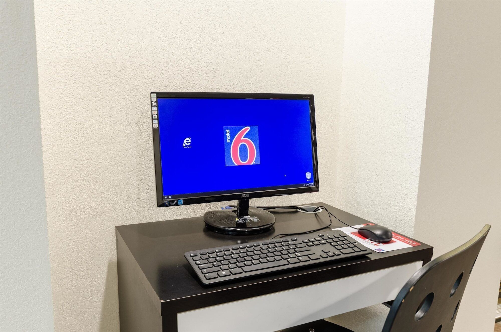 A computer setup with a monitor displaying a blue screen, a keyboard, a mouse, and a mouse pad on a desk.