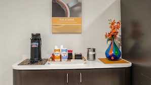 A coffee station with a coffee machine, creamer, sugar, and a vase with flowers. - Motel 6 Bristol, VA (Bristol)