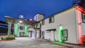 L’entrée d’un hôtel, avec un passage couvert, une enseigne indiquant le numéro de chambre « 6 », et une entrée bien dégagée.