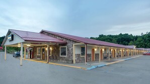 Um motel com fachada de pedra, várias acomodações e área de estacionamento coberta.