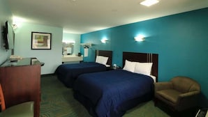 Quarto de hotel com duas camas, uma escrivaninha, uma cadeira, um espelho e um quadro na parede.